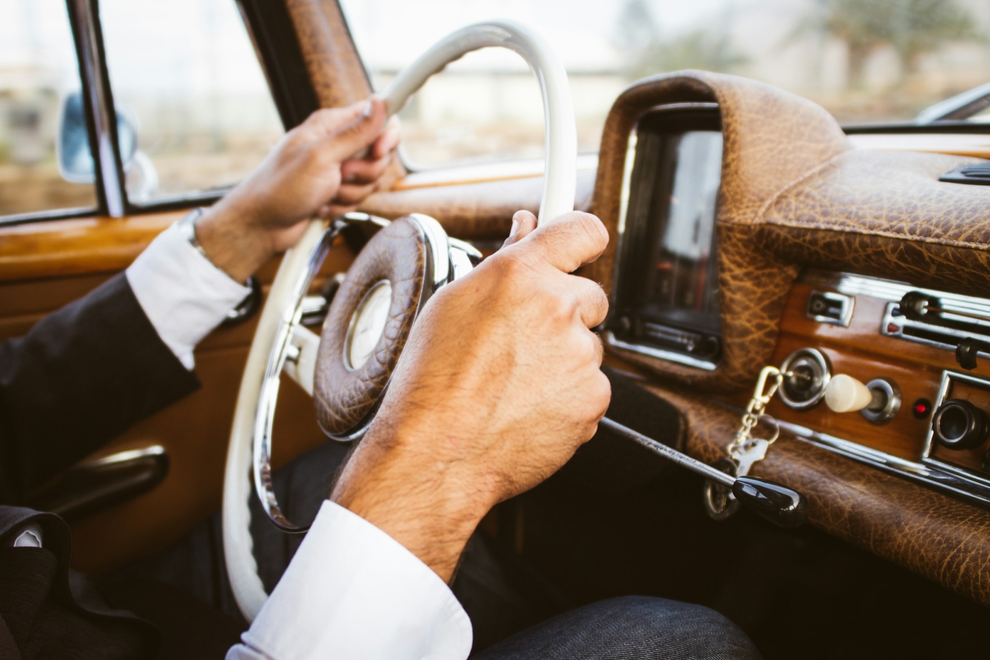 Mains sur le volant en bois d'une voiture ancienne