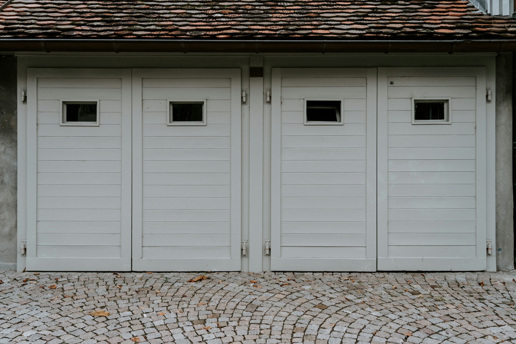 Portes de garage blanches sur une cour pavée